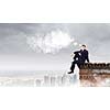 Young businessman sitting on roof of building