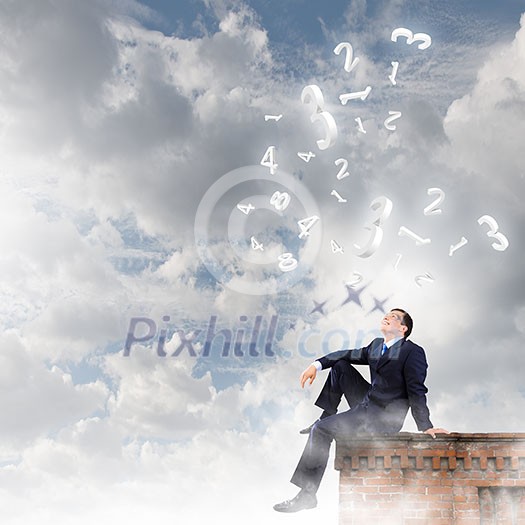 Young businessman sitting on roof of building Young businessman sitting on roof of building