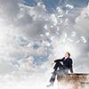 Young businessman sitting on roof of building