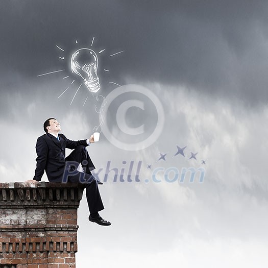 Young businessman sitting on roof of building Young businessman sitting on roof of building