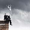 Young businessman sitting on roof of building