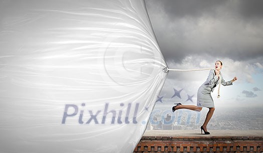 Young businesswoman running and pulling white blank banner Young businesswoman running and pulling white blank banner