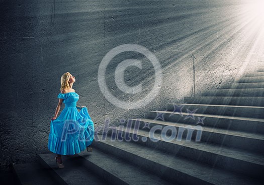 Young blond woman in blue dress walking up the stairs Young blond woman in blue dress walking up the stairs