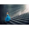 Young blond woman in blue dress walking up the stairs