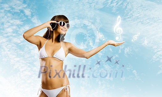 Young attractive girl in bikini wearing headphones touching media icon Young attractive girl in bikini wearing headphones touching media icon