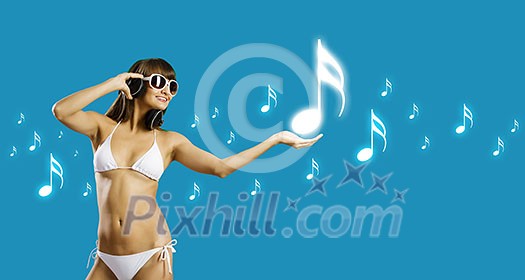 Young attractive girl in bikini wearing headphones touching media icon Young attractive girl in bikini wearing headphones touching media icon