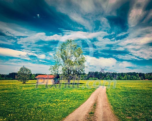 Vintage retro effect filtered hipster style image of rural road in summer meadow with wooden shed. Bavaria, Germany Vintage retro effect filtered hipster style image of rural road in summer meadow with wooden shed. Bavaria, Germany