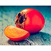 Vintage retro effect filtered hipster style image of fresh ripe persimmon with slice on a blue wooden background
