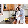 happy young couple have fun in modern wooden  kitchen indoor while preparing fresh food