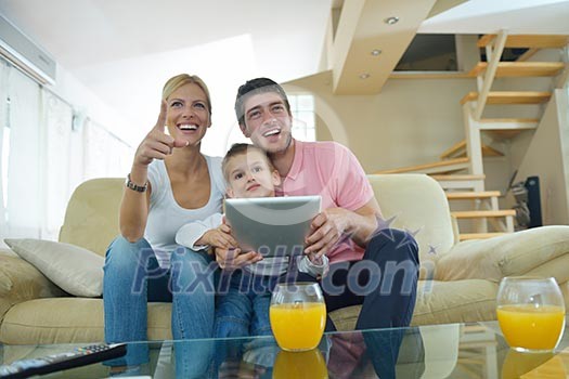 happy young family using tablet computer at modern home for playing games and education happy young family using tablet computer at modern home for playing games and education