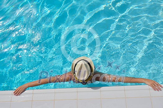 Happy smiling woman with hat and sunglasses  in swimming pool at tropical resort