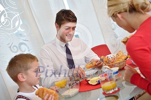happy young family have healthy breakfast at kitchen with red details on bright morning light happy young family have healthy breakfast at kitchen with red details on bright morning light