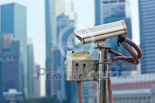 CCTV surveillance camera in Singapore with skyscapers in background CCTV surveillance camera in Singapore with skyscapers in background