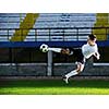 soccer player doing kick with ball on football stadium  field  isolated on black background  in night