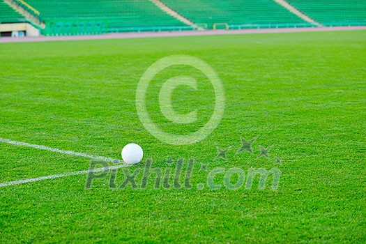 white Soccer ball on grass at goal and stadium in background white Soccer ball on grass at goal and stadium in background