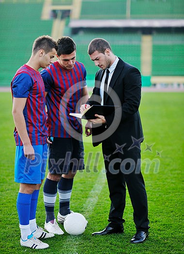 soccer sport manager in business suit coach and football player on stadium with green grass and white ball soccer sport manager in business suit coach and football player on stadium with green grass and white ball
