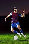 soccer player doing kick with ball on football stadium  field  isolated on black background  in night