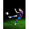 soccer player doing kick with ball on football stadium  field  isolated on black background  in night