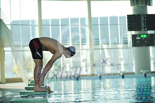 start position race concept with fit swimmer on swimming pool start position race concept with fit swimmer on swimming pool