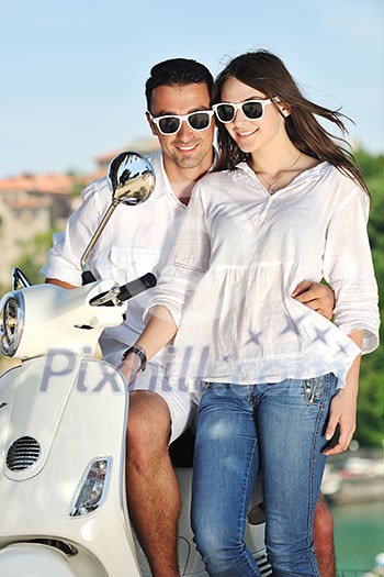 Portrait of happy young love couple on scooter enjoying themselves in a park at summer time Portrait of happy young love couple on scooter enjoying themselves in a park at summer time