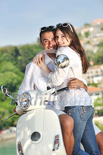 Portrait of happy young love couple on scooter enjoying themselves in a park at summer time Portrait of happy young love couple on scooter enjoying themselves in a park at summer time