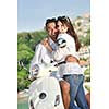 Portrait of happy young love couple on scooter enjoying themselves in a park at summer time