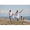 happy young family in white clothing have fun and play with beautiful dog at vacations on beautiful beach 