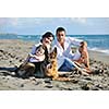 happy young family in white clothing have fun and play with beautiful dog at vacations on beautiful beach 