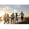 happy young friends group have fun and celebrate while jumping and running on the beach at the sunset