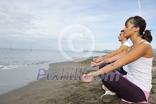 young couple people meditating yoga in lotus position at early morning on the beach young couple people meditating yoga in lotus position at early morning on the beach