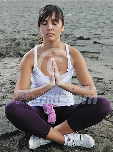 young woman meditating yoga in lotus positin on the beach at early morning young woman meditating yoga in lotus positin on the beach at early morning