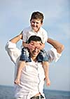 happy young  father and son have fun and enjoy time on beach at sunset and representing healthy family and support concept