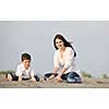 happy young mother  and son relaxing and play ind sand games on beach at summer season
