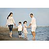 happy young family have fun on beach run and jump  at sunset