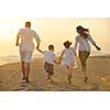 happy young family have fun on beach run and jump  at sunset
