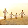 happy young family have fun on beach run and jump  at sunset