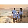 happy young family have fun on beach run and jump  at sunset
