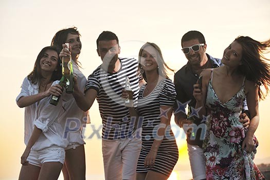 Group of young people enjoy summer party at the beach on beautiful sunset Group of young people enjoy summer party at the beach on beautiful sunset