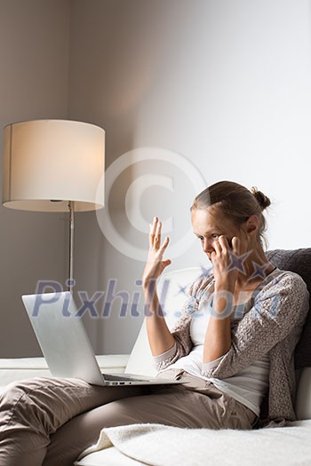 Very tired young woman, burning the midnigh oil - working late at night on her laptop computer, at home, sitting on sofa, rubbing her tired eyes, trying to stay focused Very tired young woman, burning the midnigh oil - working late at night on her laptop computer, at home, sitting on sofa, rubbing her tired eyes, trying to stay focused