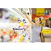 Beautiful young woman shopping for diary products at a grocery store/supermarket (color toned image)