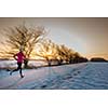 Young woman stretching while running outdoors on a cold winter evening