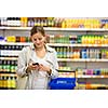 Pretty, young woman buying groceries in a supermarket/mall/gr ocery store (color toned image; shallow DOF)