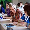 Handsome college student sitting in a classroom full of students during class  (color toned image; shallow DOF)