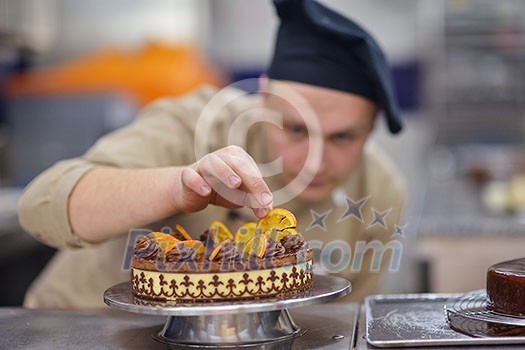 Closeup of a concentrated male pastry chef decorating dessert cake food in the kitchen Closeup of a concentrated male pastry chef decorating dessert cake food in the kitchen