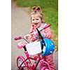 Cute smiling little girl with bicycle and helmet on road in the park