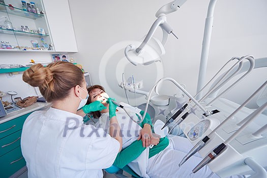 Closeup of a woman patient at the dentist waiting to be checked up with the woman doctor in the background Closeup of a woman patient at the dentist waiting to be checked up with the woman doctor in the background