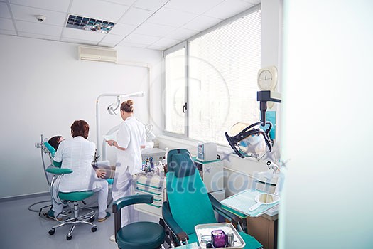 Closeup of a woman patient at the dentist waiting to be checked up with the woman doctor in the background Closeup of a woman patient at the dentist waiting to be checked up with the woman doctor in the background