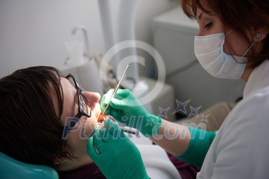 Closeup of a woman patient at the dentist waiting to be checked up with the woman doctor in the background Closeup of a woman patient at the dentist waiting to be checked up with the woman doctor in the background