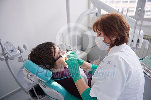 Closeup of a woman patient at the dentist waiting to be checked up with the woman doctor in the background Closeup of a woman patient at the dentist waiting to be checked up with the woman doctor in the background