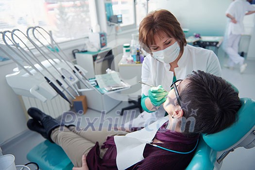 Closeup of a woman patient at the dentist waiting to be checked up with the woman doctor in the background Closeup of a woman patient at the dentist waiting to be checked up with the woman doctor in the background